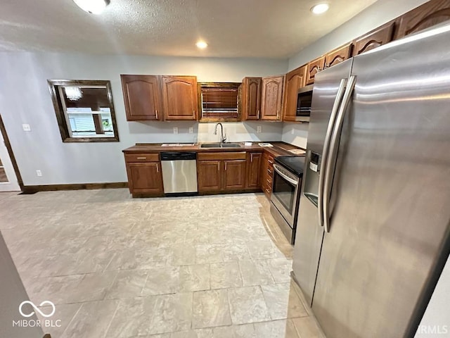 kitchen featuring baseboards, a sink, recessed lighting, and stainless steel appliances