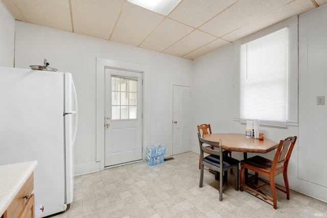 dining space with light floors and a drop ceiling