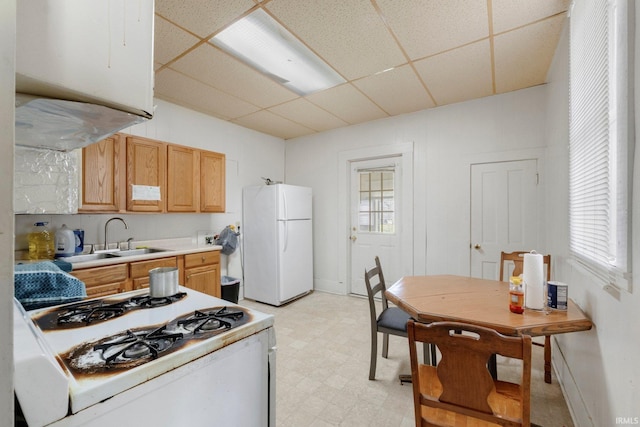 kitchen with white appliances, light floors, light countertops, a paneled ceiling, and a sink