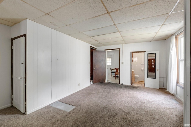 carpeted spare room featuring a drop ceiling and a wealth of natural light