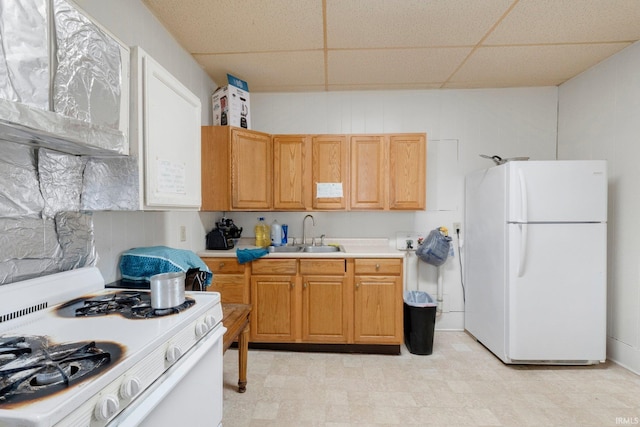 kitchen featuring a sink, white appliances, light countertops, a paneled ceiling, and light floors