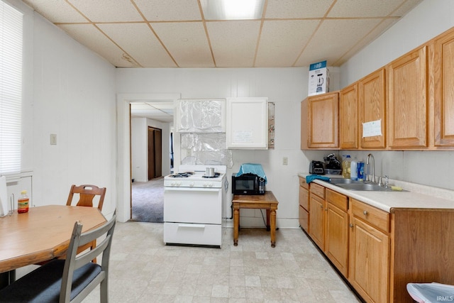 kitchen featuring white gas stove, black microwave, a sink, light countertops, and a drop ceiling