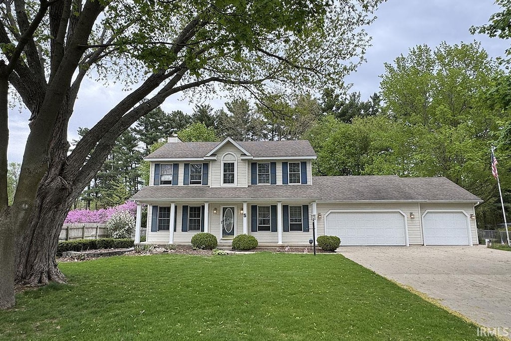 5 Shore Manor Dr, Bristol, IN 46507 - colonial-style house with a porch, a front yard, fence, concrete driveway, and an attached garage