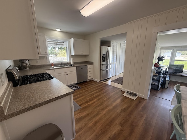 kitchen with a sink, dark wood-style flooring, appliances with stainless steel finishes, and white cabinets