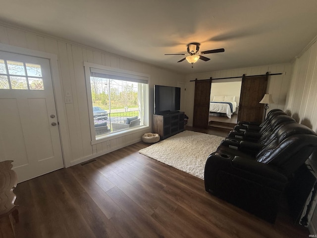 living room featuring visible vents, a barn door, ceiling fan, and a wealth of natural light