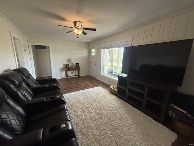living room with a ceiling fan, visible vents, baseboards, dark wood-style floors, and ornamental molding