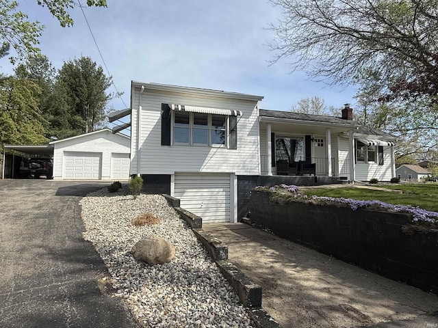 view of front of property with a porch, an outbuilding, driveway, and a chimney