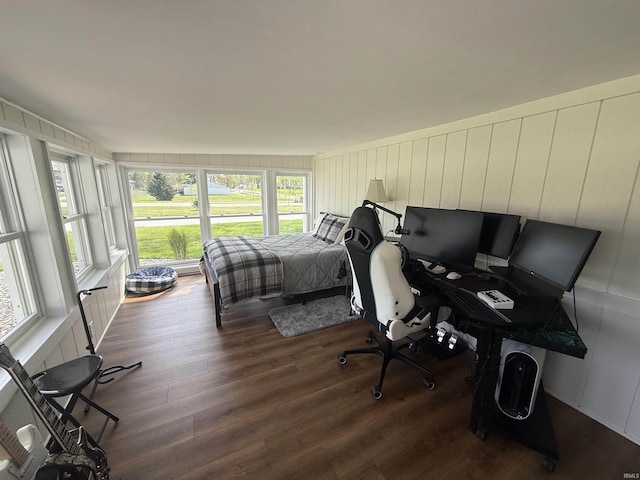 bedroom with multiple windows, wood finished floors, and a decorative wall
