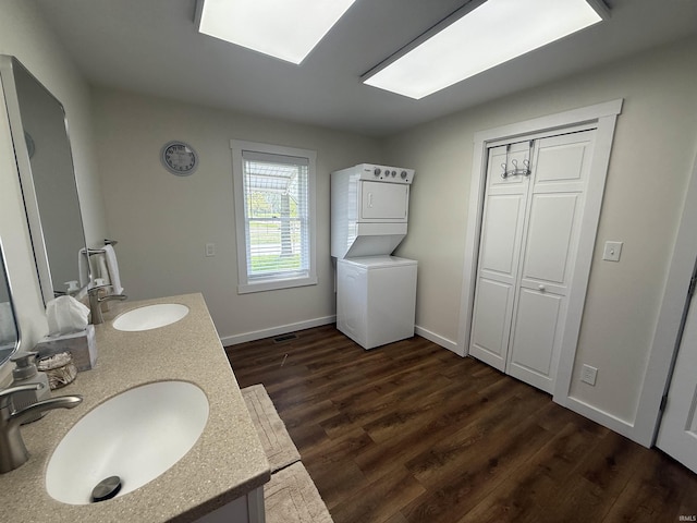 bathroom featuring stacked washer / drying machine, a sink, and wood finished floors