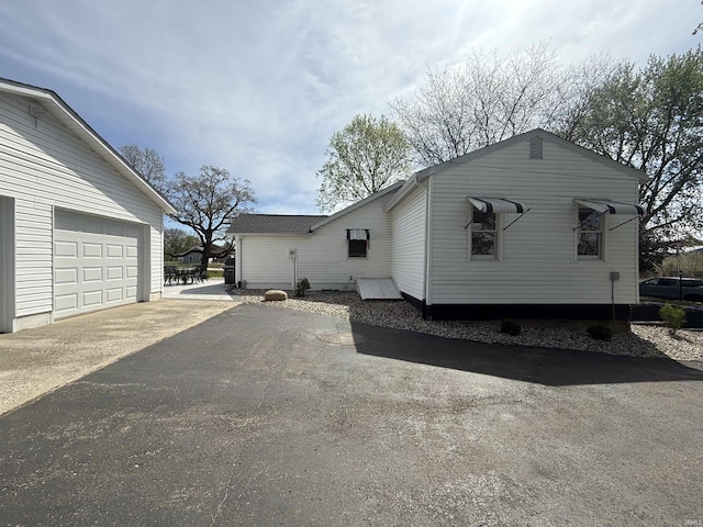 view of side of home with a garage and aphalt driveway