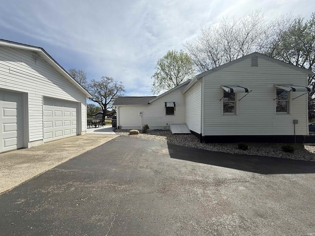 view of side of home featuring a garage and aphalt driveway