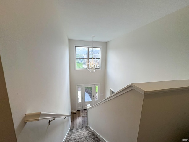 stairway featuring baseboards, a high ceiling, an inviting chandelier, and a healthy amount of sunlight