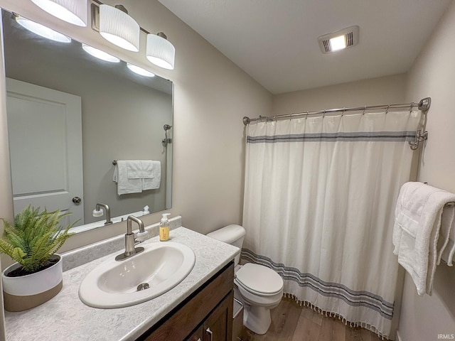 bathroom with visible vents, vanity, wood finished floors, toilet, and a shower with curtain