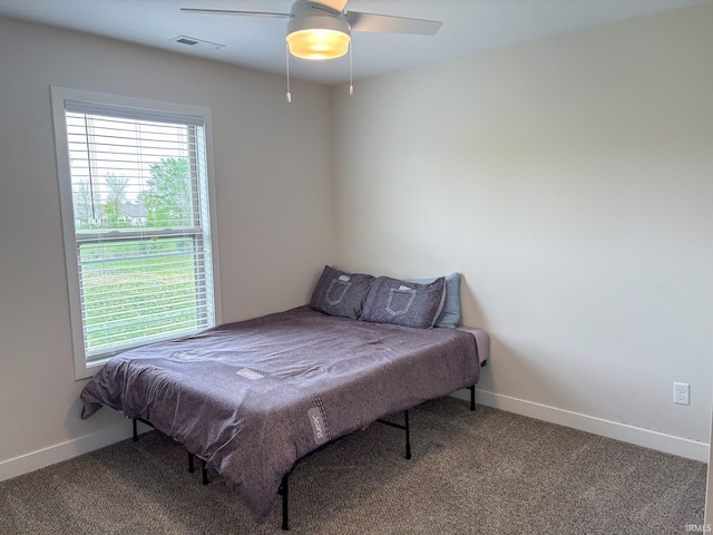 carpeted bedroom with baseboards, multiple windows, ceiling fan, and visible vents