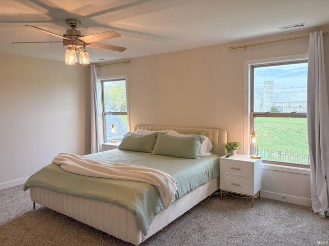 carpeted bedroom with baseboards, a ceiling fan, and visible vents