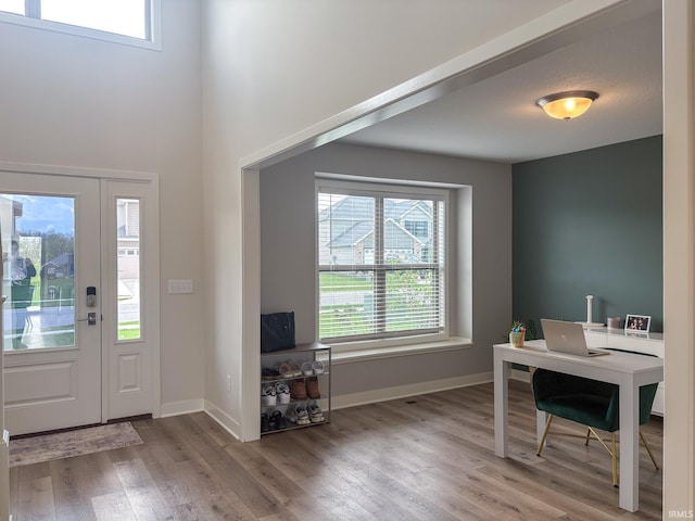 entryway featuring baseboards, wood finished floors, and a towering ceiling