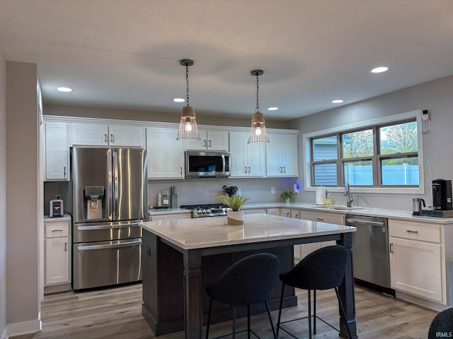 kitchen featuring a kitchen island, stainless steel appliances, white cabinetry, and a sink