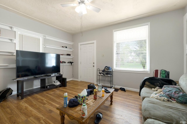 living area featuring baseboards, ceiling fan, and wood finished floors