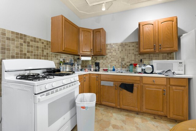 kitchen with white appliances, decorative backsplash, a sink, and light countertops