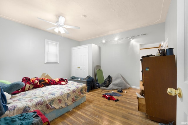 bedroom with rail lighting, ceiling fan, and wood finished floors