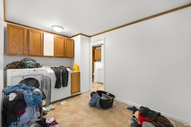 washroom with baseboards, ornamental molding, cabinet space, and washing machine and dryer