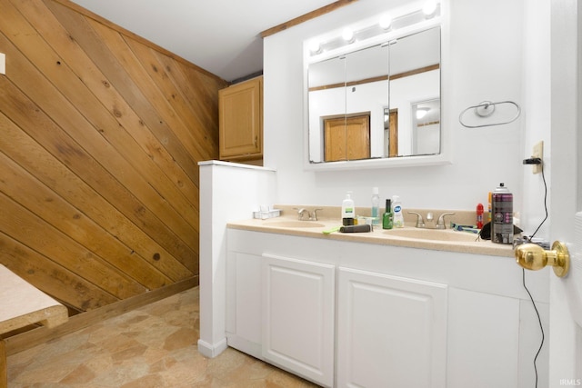 full bath with double vanity, a sink, and wood walls