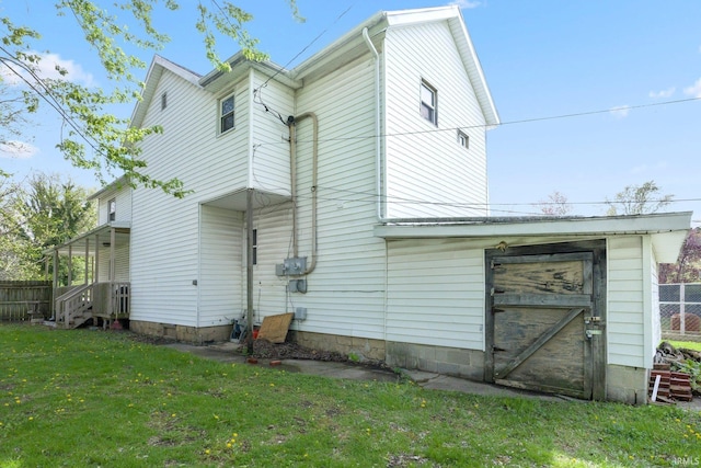 rear view of property featuring a lawn and fence