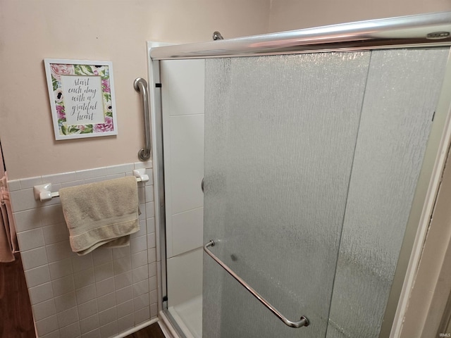 bathroom featuring tile walls, a wainscoted wall, and a shower stall