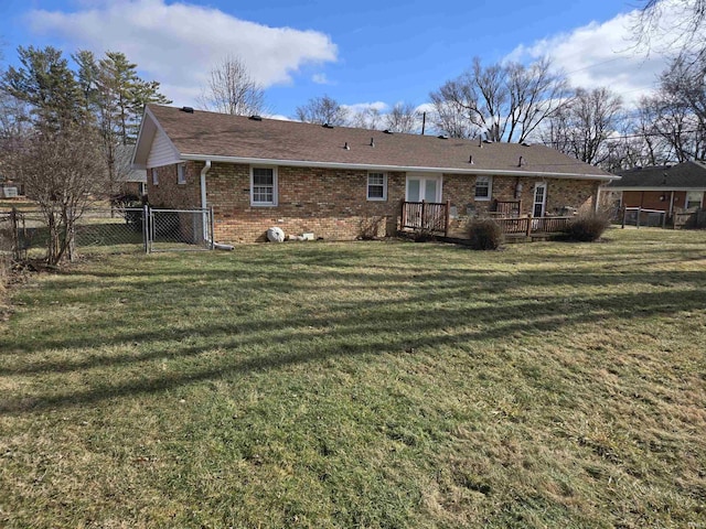 back of house with brick siding, fence, a yard, and a wooden deck