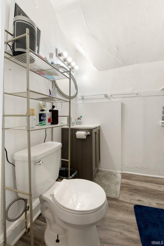 half bathroom with toilet, baseboards, wood finished floors, and vanity