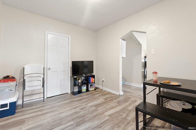interior space with arched walkways, baseboards, and light wood-type flooring