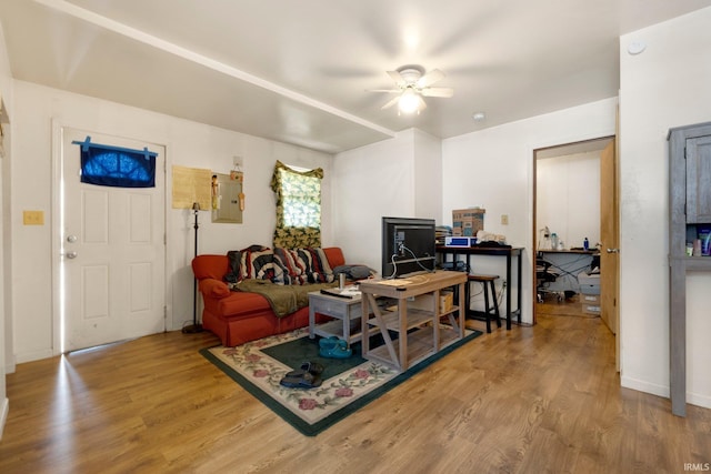 living area featuring baseboards, ceiling fan, wood finished floors, and electric panel