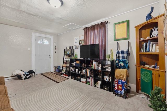 carpeted living room featuring attic access, a baseboard heating unit, and a textured ceiling