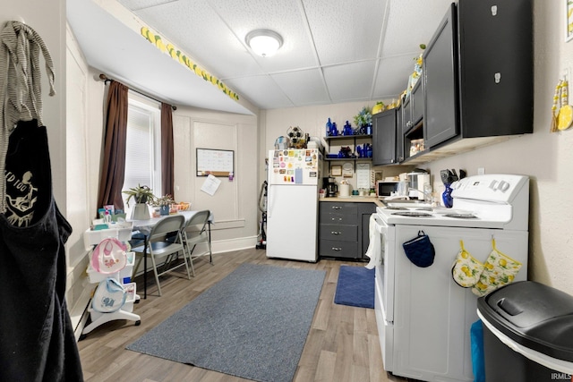 kitchen featuring open shelves, freestanding refrigerator, light wood finished floors, washer / dryer, and a drop ceiling