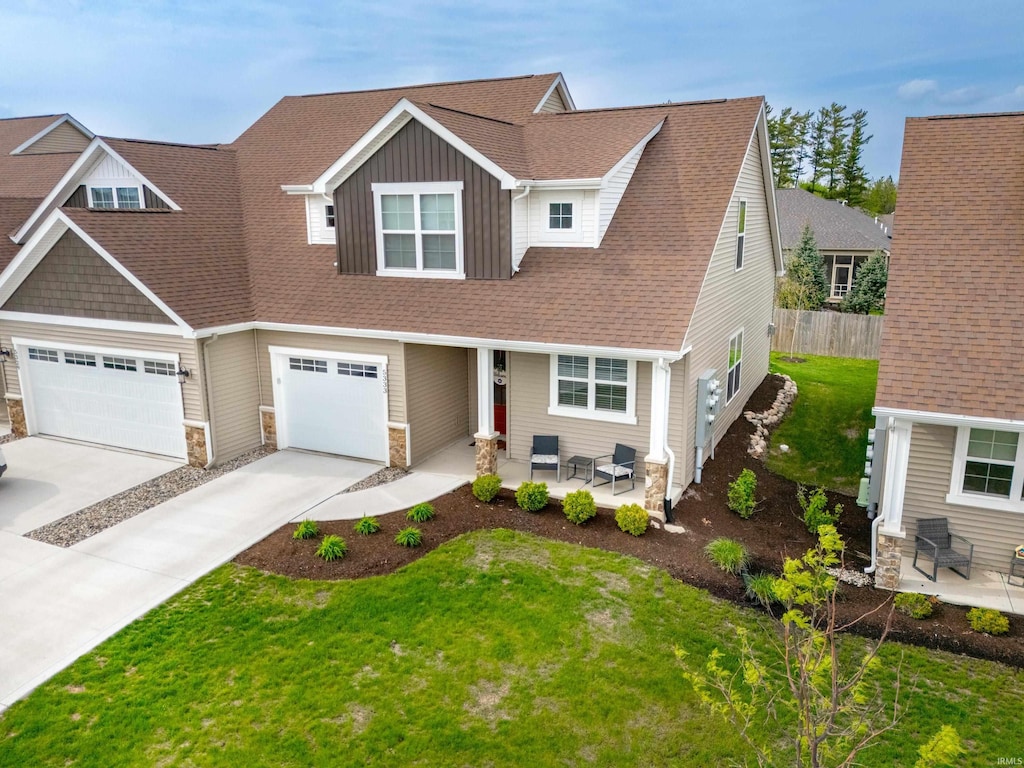 view of front of property with board and batten siding, driveway, a garage, a front lawn, and stone siding