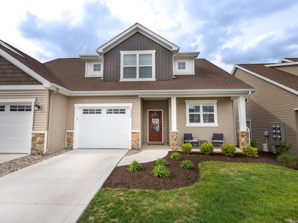 craftsman house featuring a porch, driveway, and stone siding