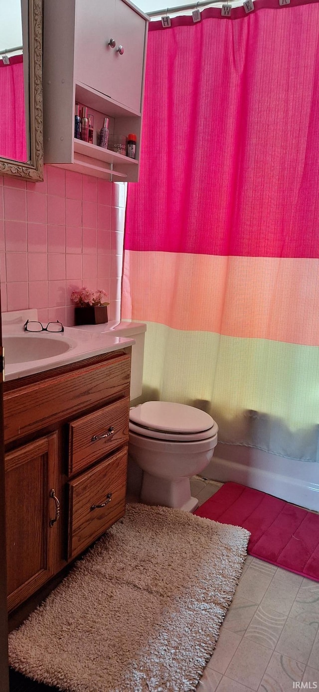 bathroom featuring toilet, tile walls, tasteful backsplash, and vanity