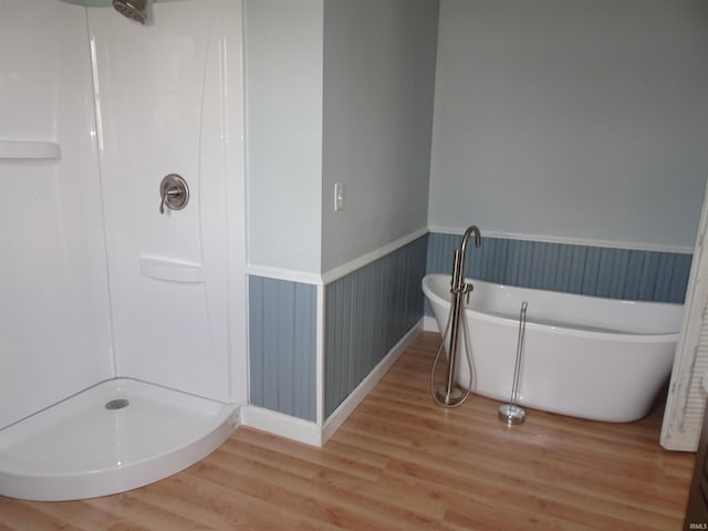 bathroom featuring a freestanding tub, walk in shower, wainscoting, and wood finished floors