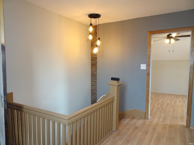 corridor with light wood-type flooring and an upstairs landing