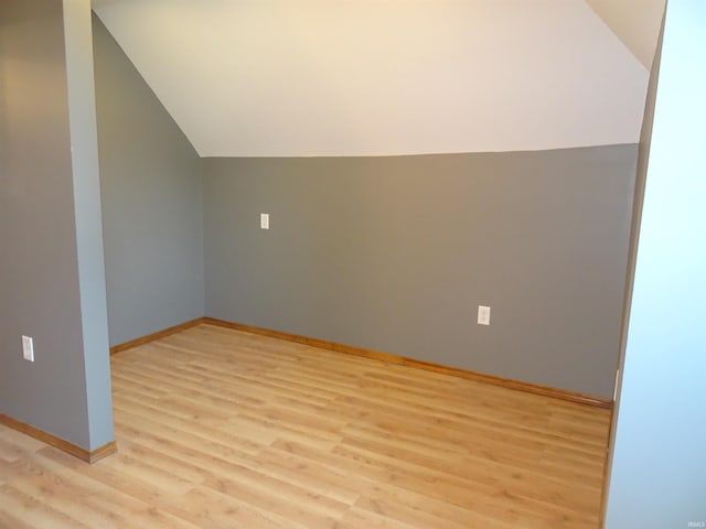 bonus room featuring light wood-style floors, baseboards, and vaulted ceiling
