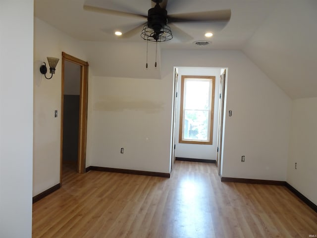 additional living space featuring ceiling fan, visible vents, vaulted ceiling, baseboards, and light wood-style flooring