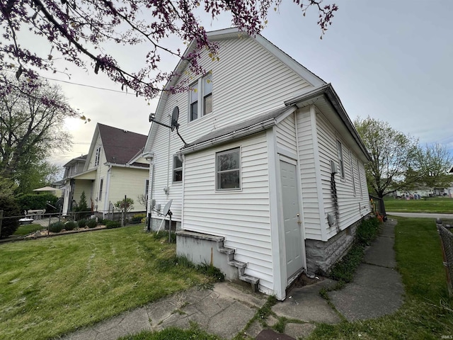 view of home's exterior with a lawn and fence