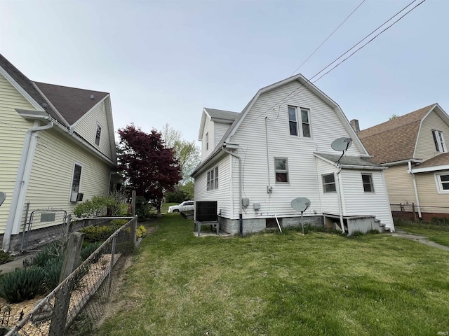 back of house featuring a lawn, fence, and a gambrel roof