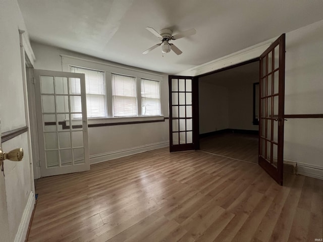 empty room featuring baseboards, ceiling fan, french doors, and wood finished floors