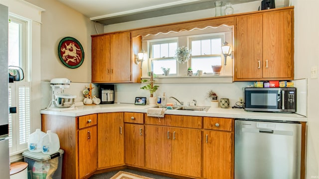 kitchen featuring light countertops, a sink, appliances with stainless steel finishes, and a wealth of natural light