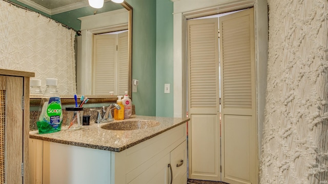bathroom featuring vanity, ornamental molding, and a closet