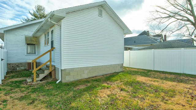 view of property exterior featuring a yard, fence, and entry steps