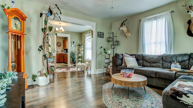 living room with a healthy amount of sunlight, baseboards, an inviting chandelier, and wood finished floors