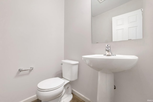 bathroom with toilet, baseboards, and a sink