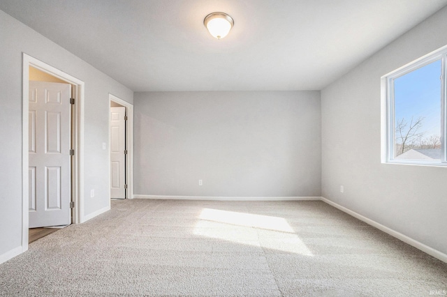 unfurnished bedroom with baseboards, multiple windows, and carpet